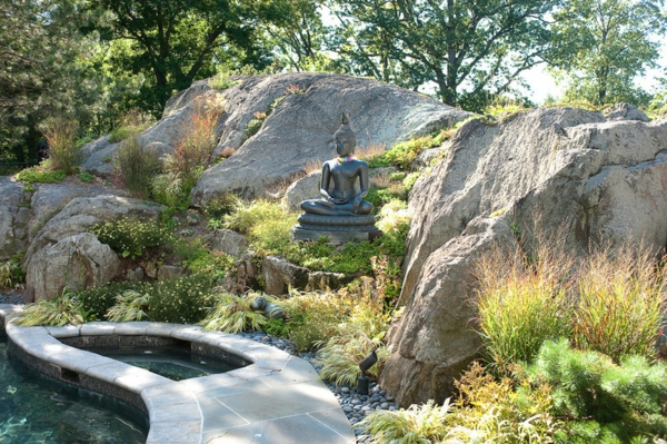 Figuras de Buda en el jardín follaje verde piedras roca