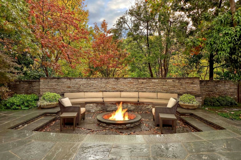 Diseño de jardín de construcción de pozo de fuego con sillón de mimbre de piedras
