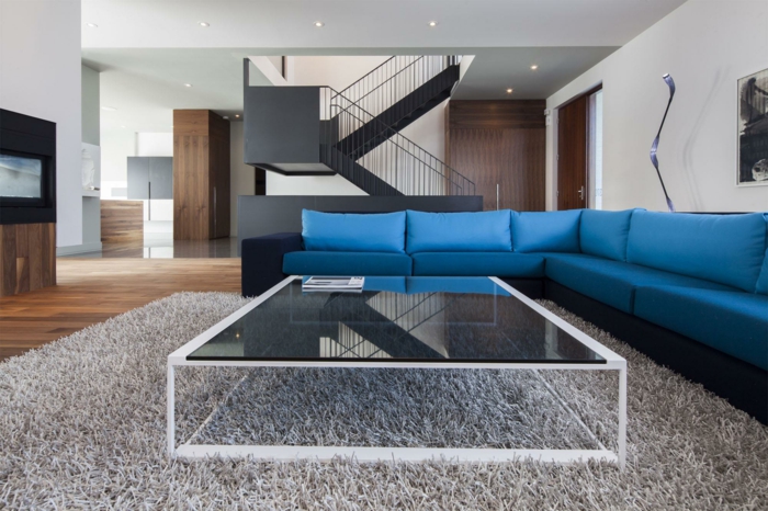 blauwe sofa hoekbank glazen salontafel beige tapijt