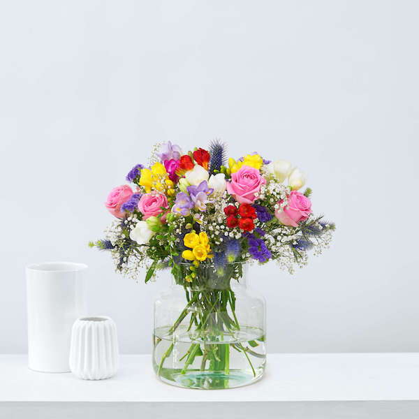 kleurrijk bloemstuk van transparante vaas