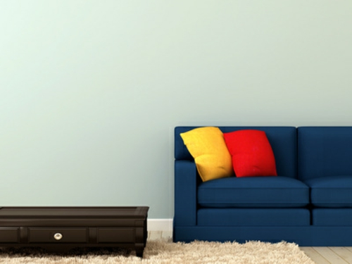 Sininen sohva värikkäillä tyynyillä ja sohvapöydän koristeluilla
