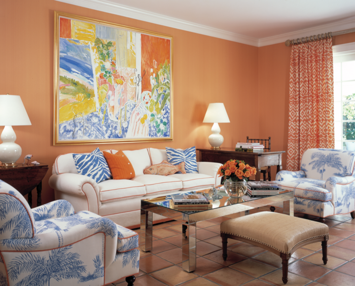 kleurstelling woonkamer oranje muren schilderijen lange gordijnen stof patroon