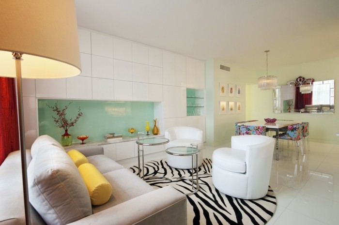 diseño de interiores sala de estar abierta art deco alfombra redonda cebra luz verde cocina pared posterior