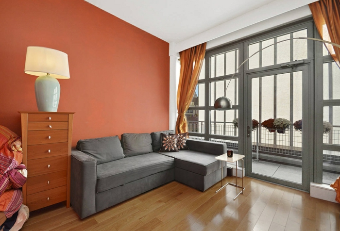 interiér životní styl nápady obývací pokoj šedá rohová pohovka oranžový přízvuk stěna