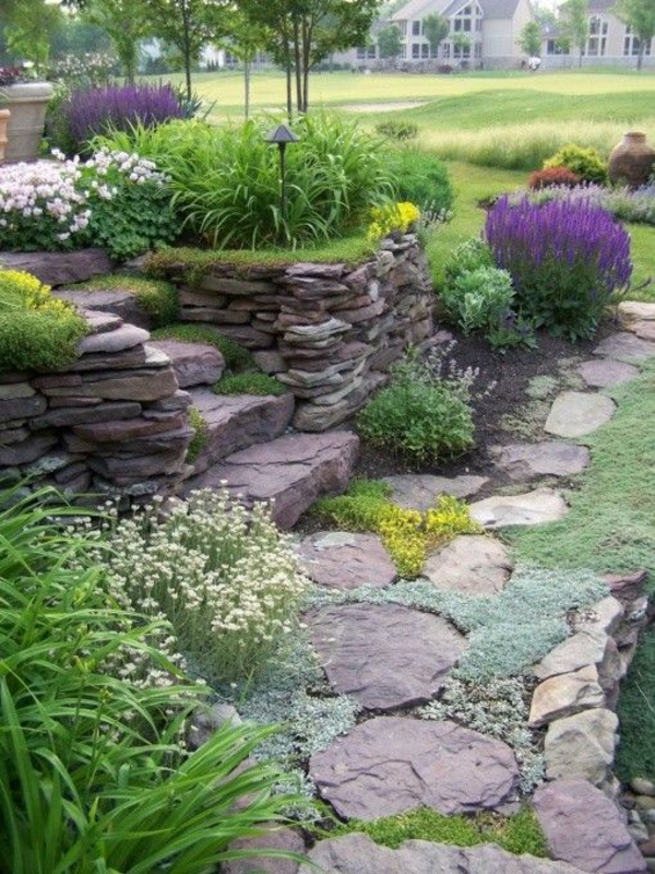 πέτρινο κήπο με πέτρινο τοίχο στοιβάζονται πέτρες πολύχρωμα φυτά