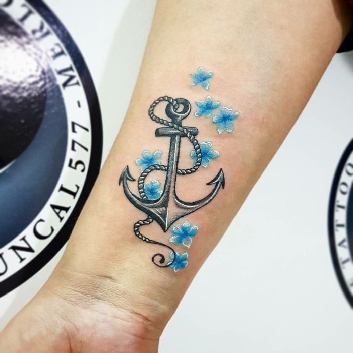 idées de tatouage pour les femmes ancre sur l'avant-bras avec des fleurs bleues