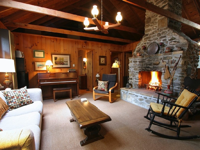 woonkamer stenen muur open haard rustieke salontafel schommelstoel landelijke stijl