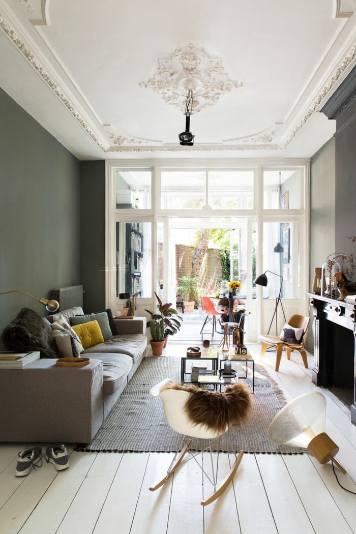 kleurstelling woonkamer grijze muren schommelstoel tapijt planten