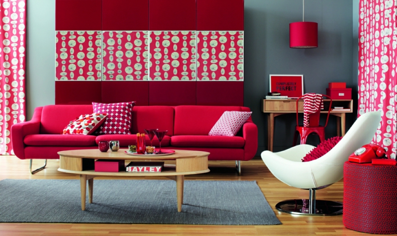 Червената стена на чертежите в дневната се съчетава със студени и топли цветове